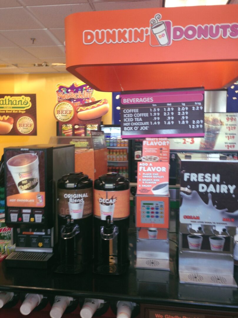 A dunkin donuts store with coffee machines and drinks.