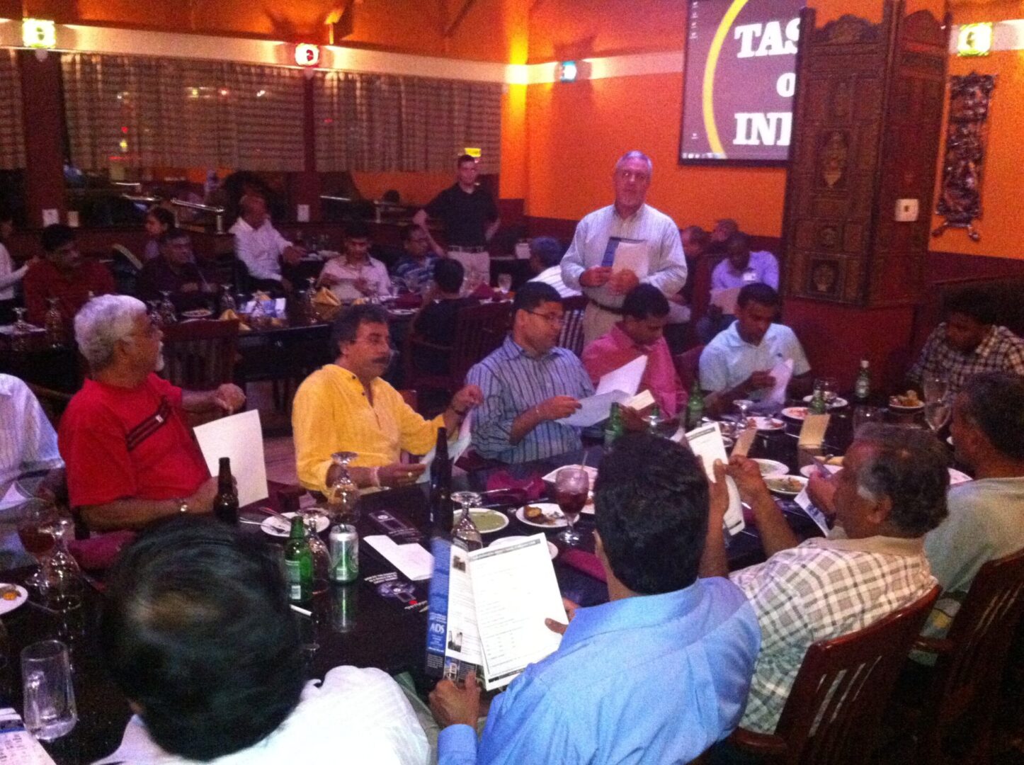 A group of people sitting around tables in front of microphones.