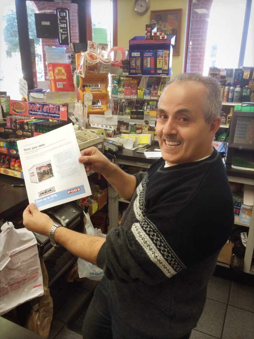 A man holding up a paper in front of a store.