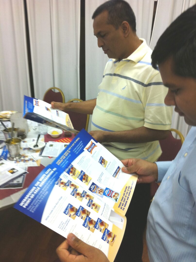 Two men looking at a calendar on top of a table.